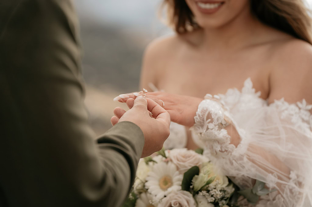 Couple exchanging wedding rings with flowers.