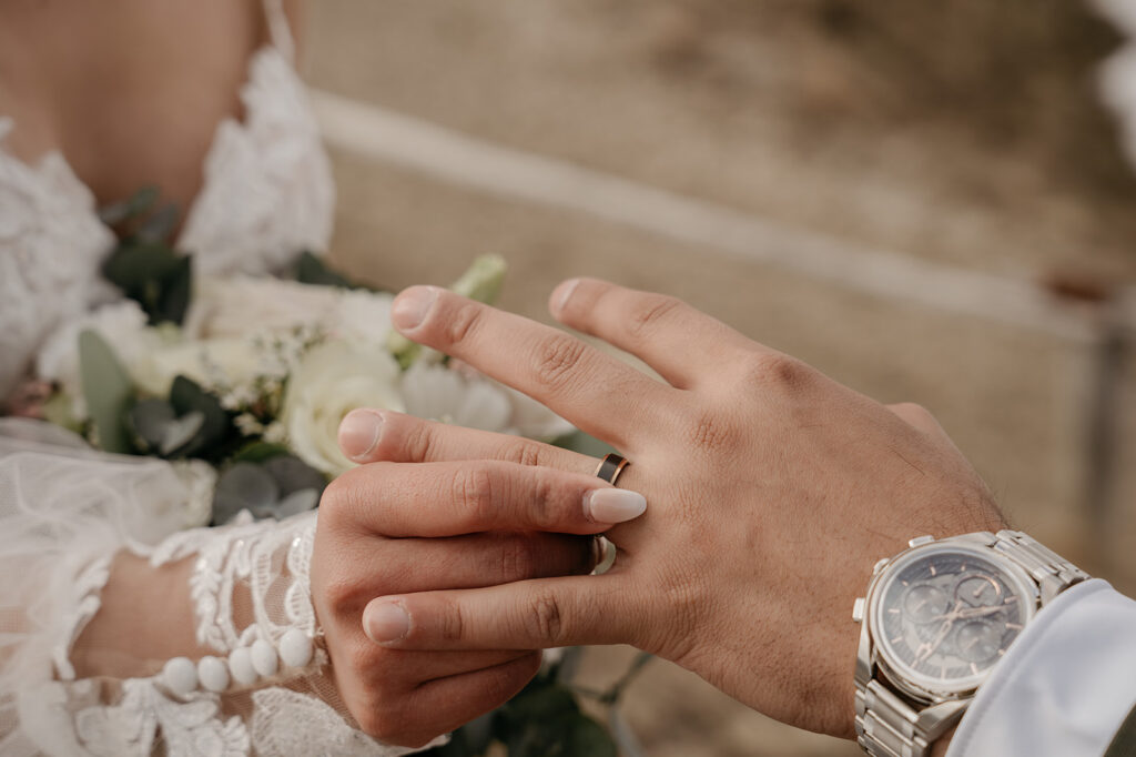 Wedding couple exchanging rings outdoors.