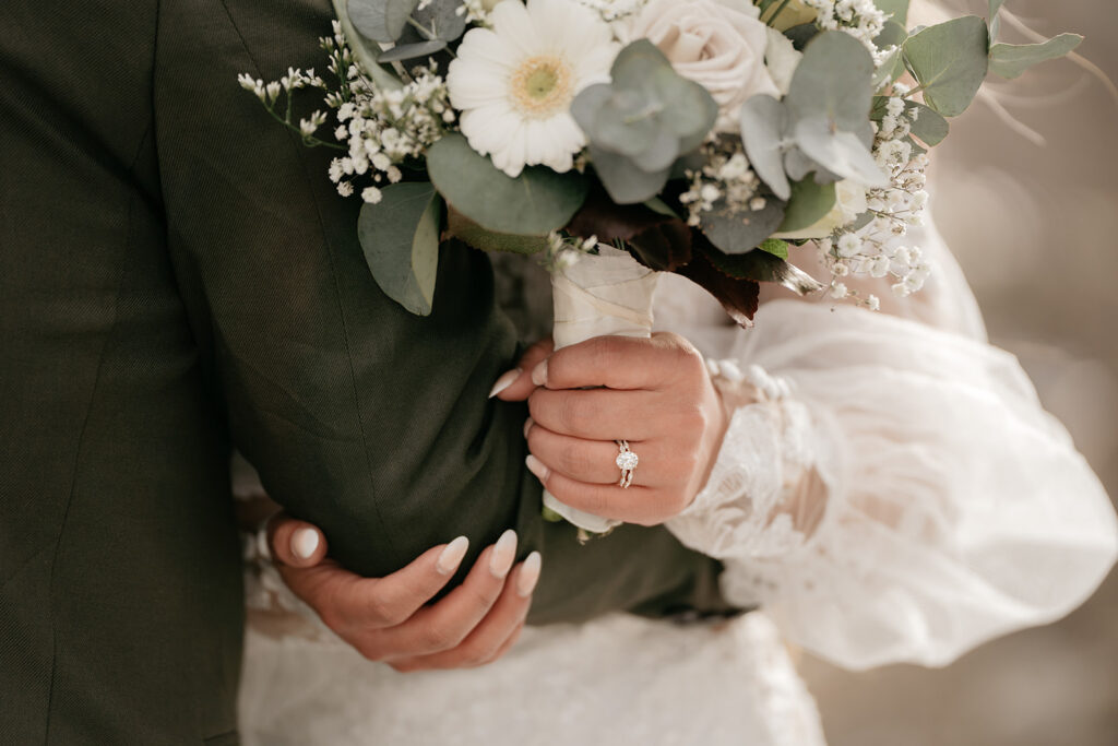 Bride holding bouquet and groom's arm, wedding scene