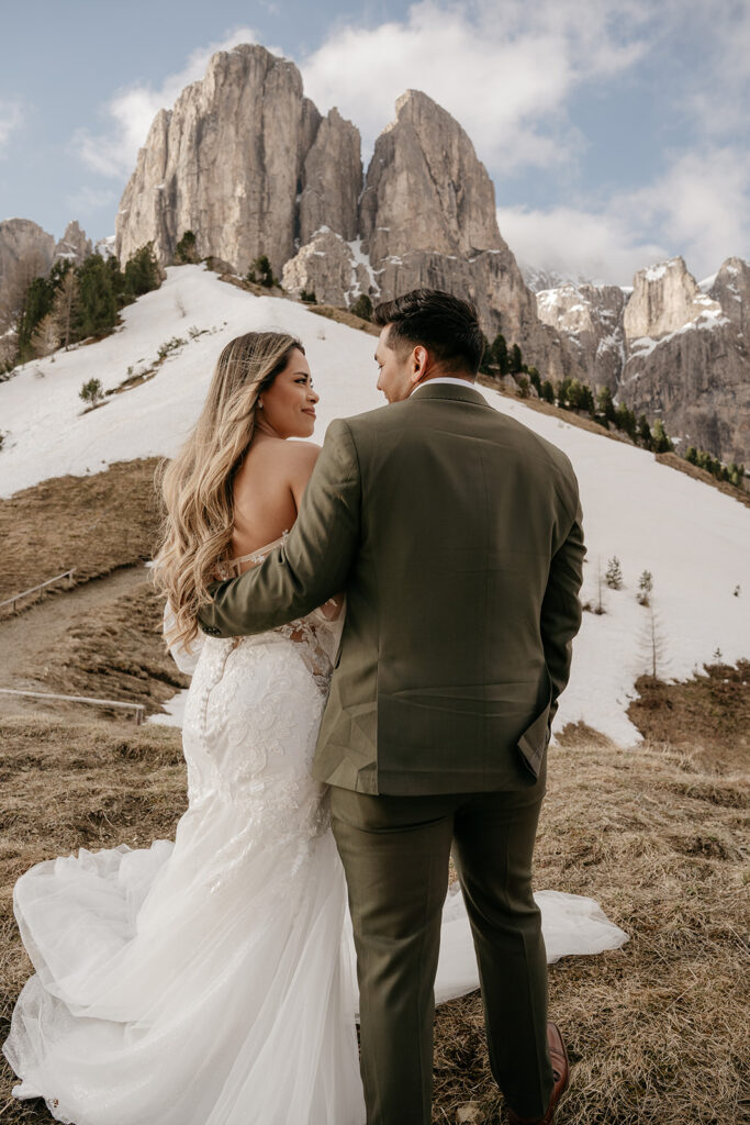 Couple in wedding attire at snowy mountain backdrop.