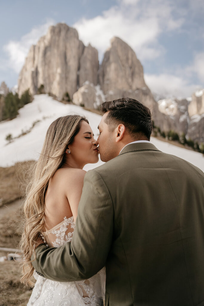 Couple kissing in snowy mountain landscape.