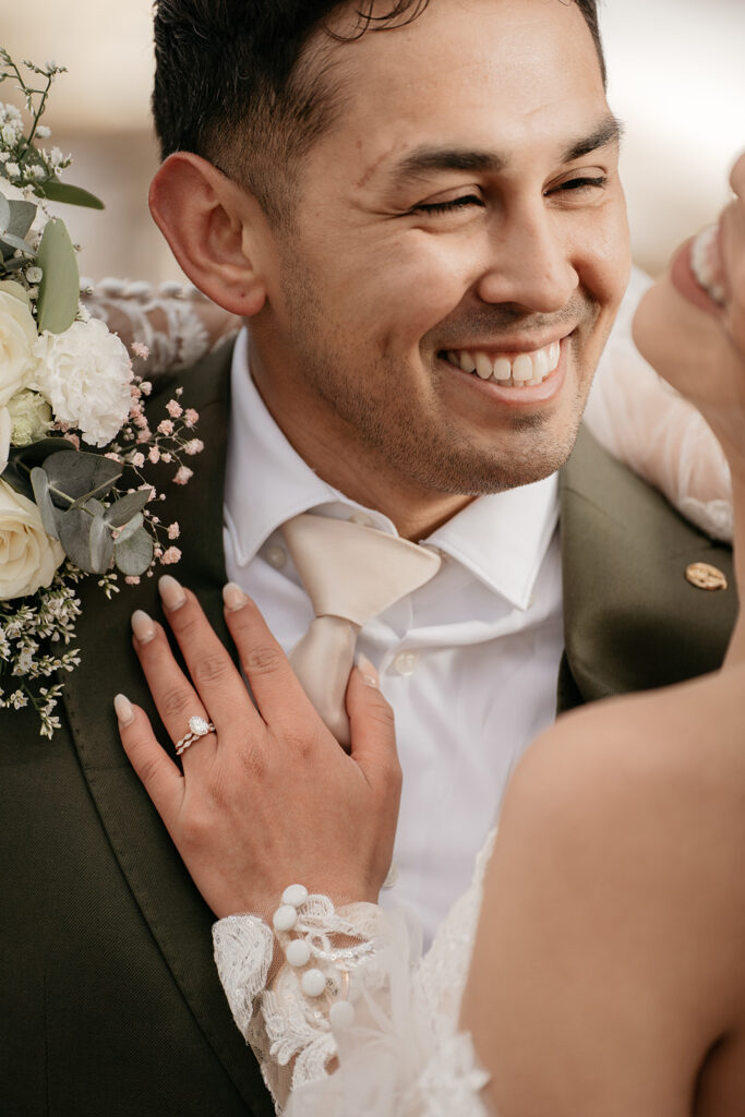 Smiling groom with bride and floral bouquet.