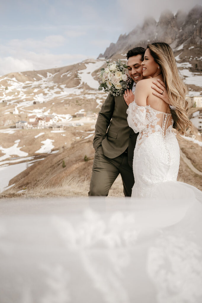 Bride and groom embrace in mountainous landscape