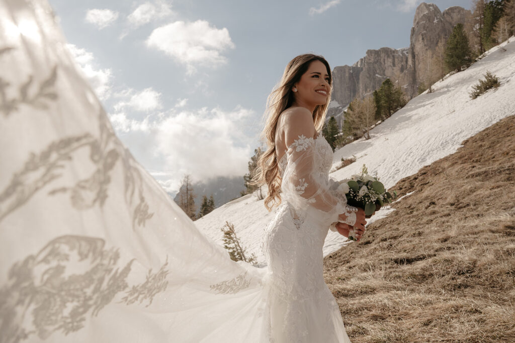 Bride in mountains with lace dress and bouquet.