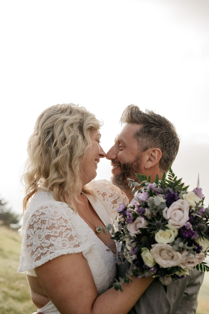 Couple embracing outdoors with flowers.