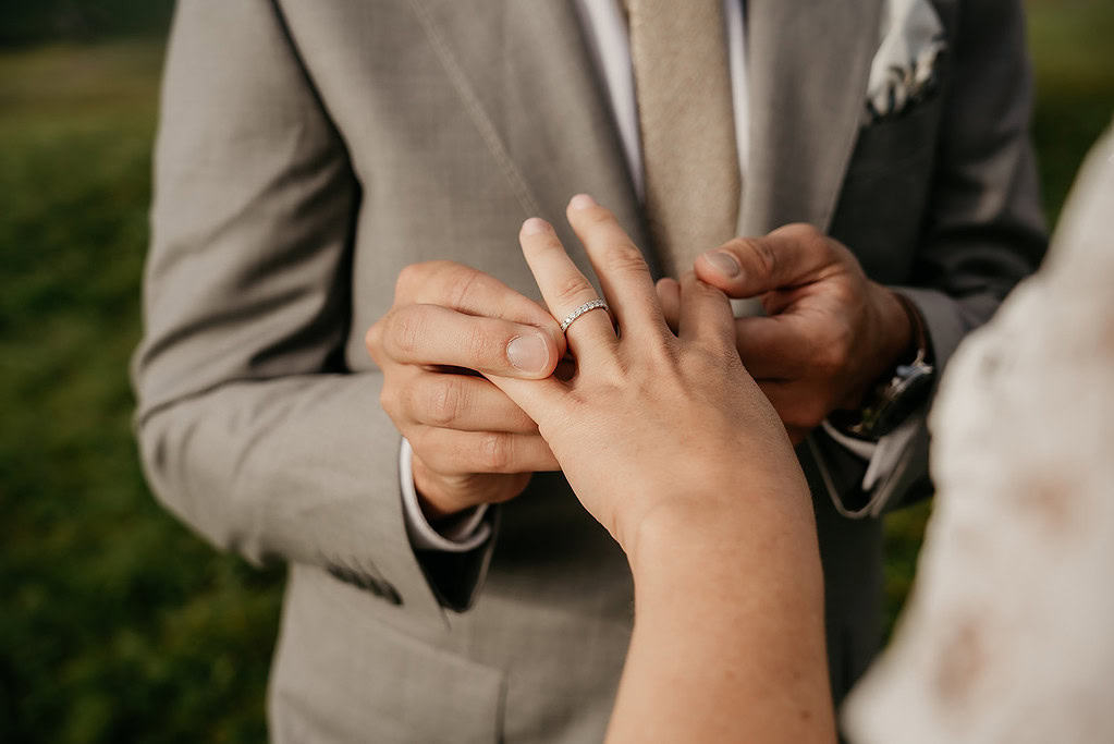 Couple exchanging wedding rings outdoors.