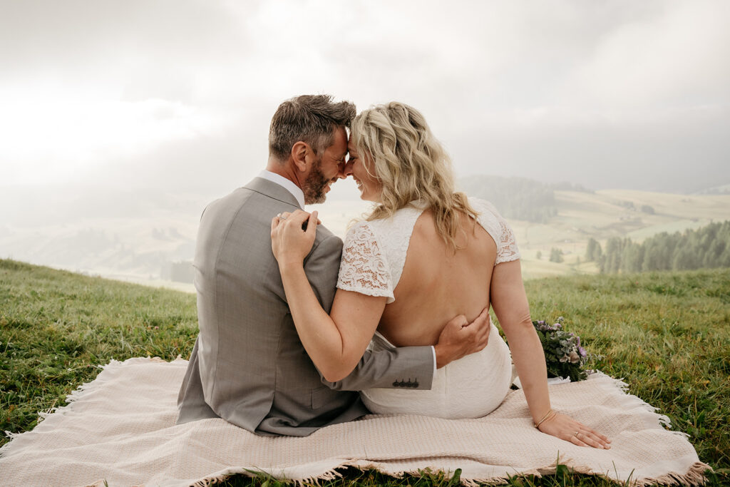 Couple embracing on a scenic grassy hill.