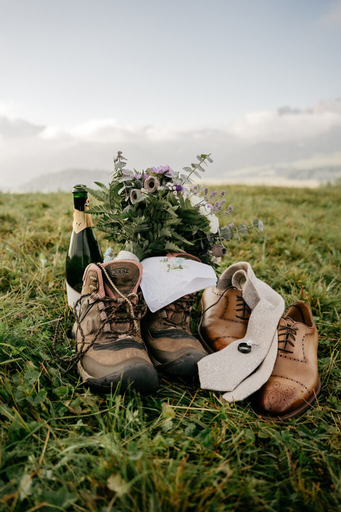 Hiking boots and dress shoes with bouquet in field.