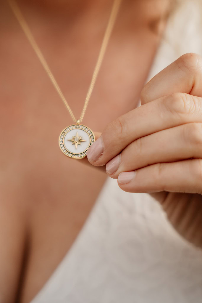 Woman holding gold star necklace pendant.