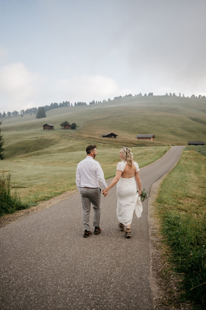 Bride and groom holding hands on countryside road