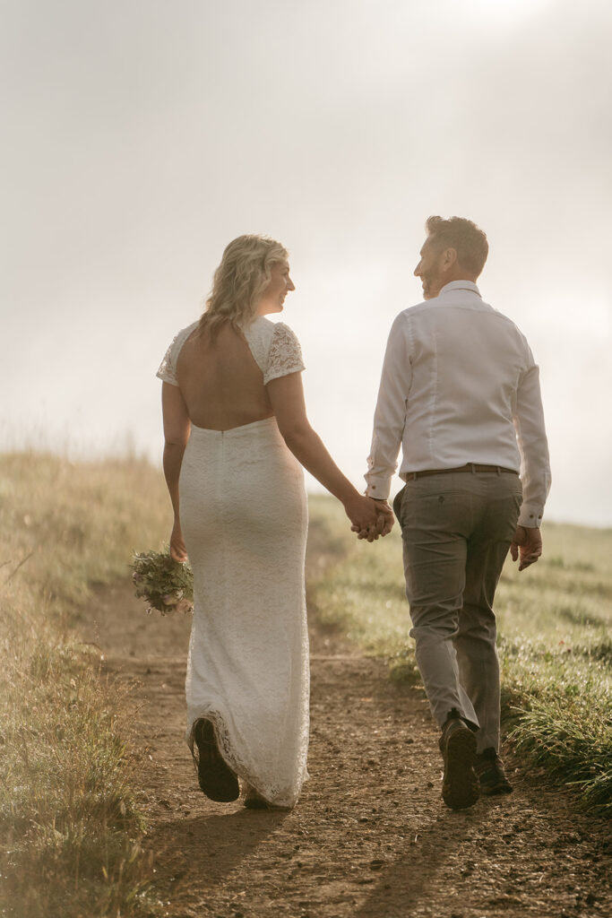 Couple walking hand in hand on grassy path