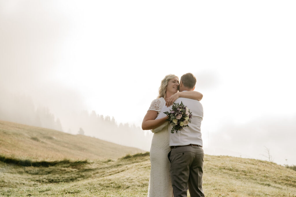 Bride and groom embracing in a serene field