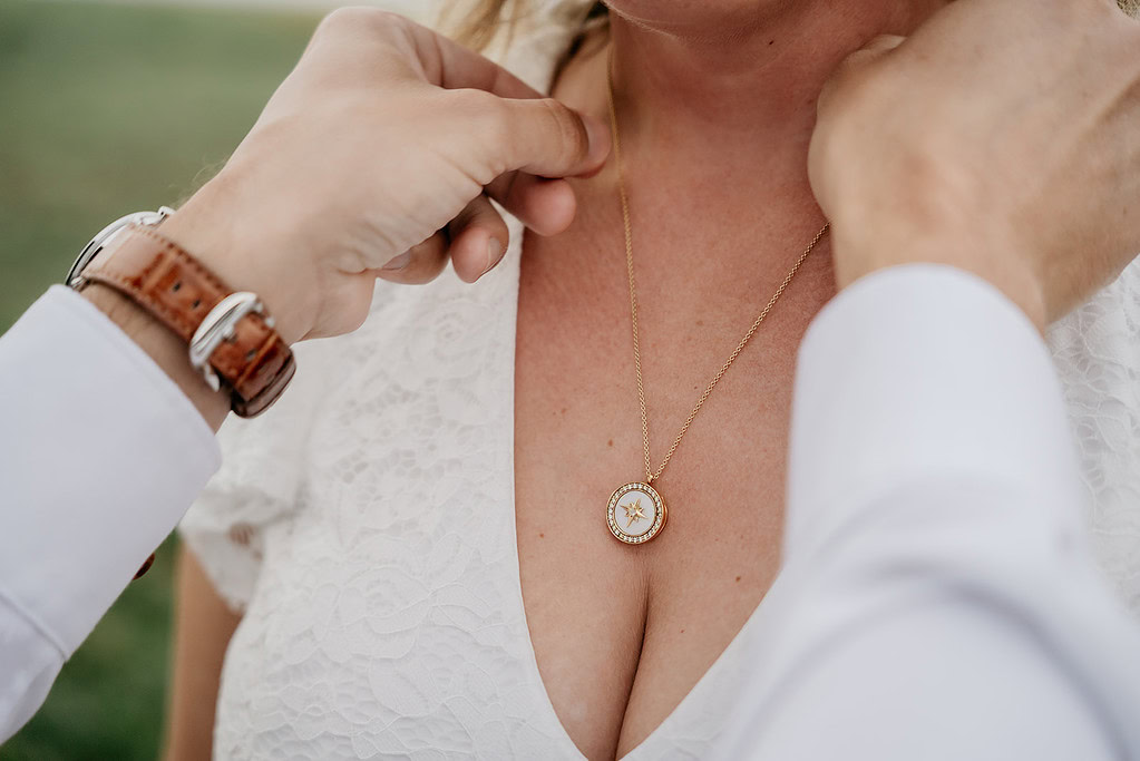 Hand adjusting necklace on woman's neck