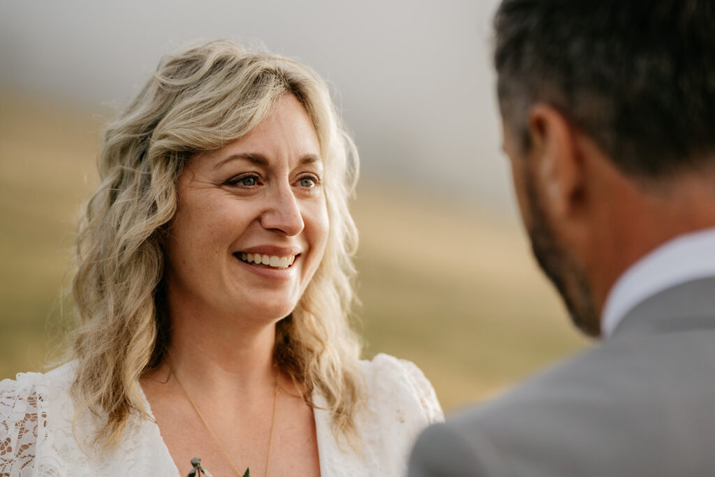 Smiling woman during outdoor wedding ceremony.