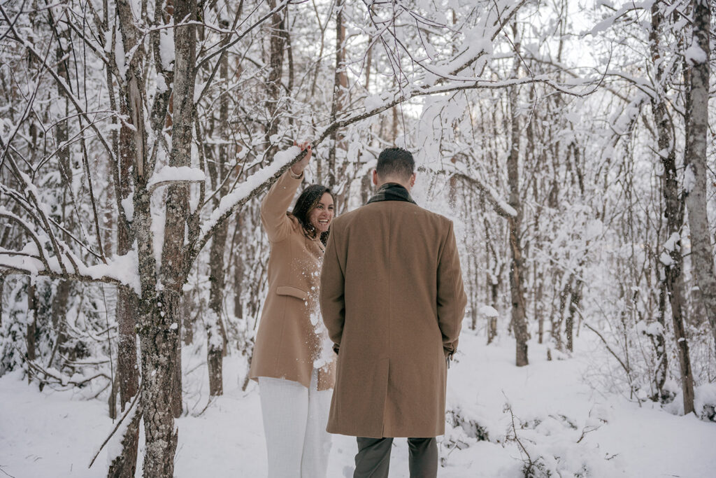 Couple playing in snowy forest, woman smiling