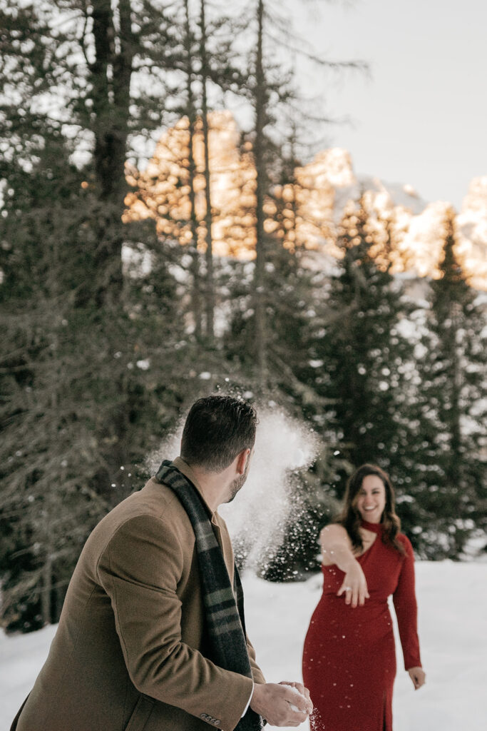 Couple throwing snowballs in snowy forest.