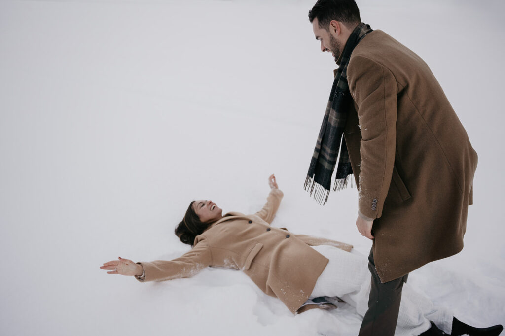 Couple playing in snow, wearing winter coats.