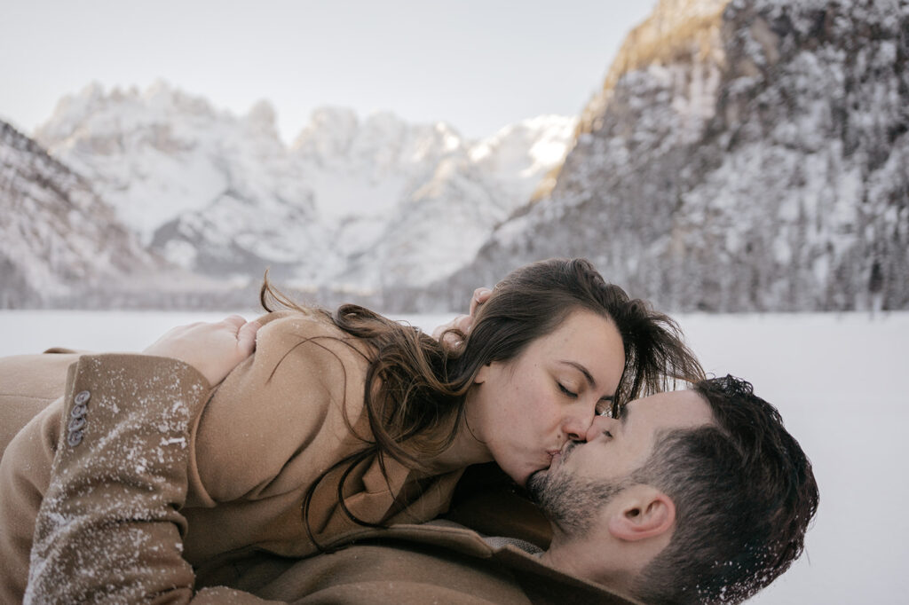 Couple kissing in snowy mountain landscape.