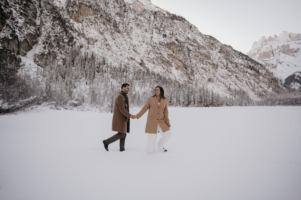 Couple walking on snow by snowy mountain landscape