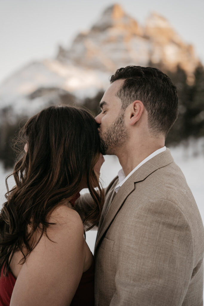 Couple embracing with snowy mountain backdrop.