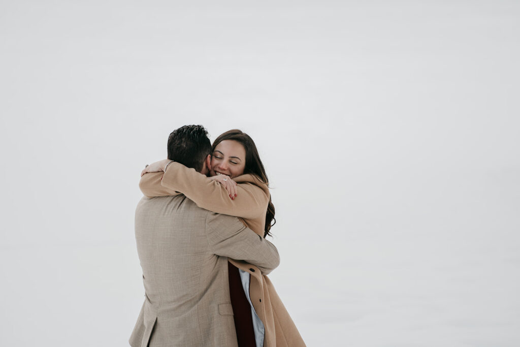 Couple embracing joyfully in winter scenery.