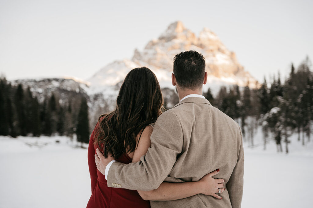 Couple embracing with snowy mountain backdrop.