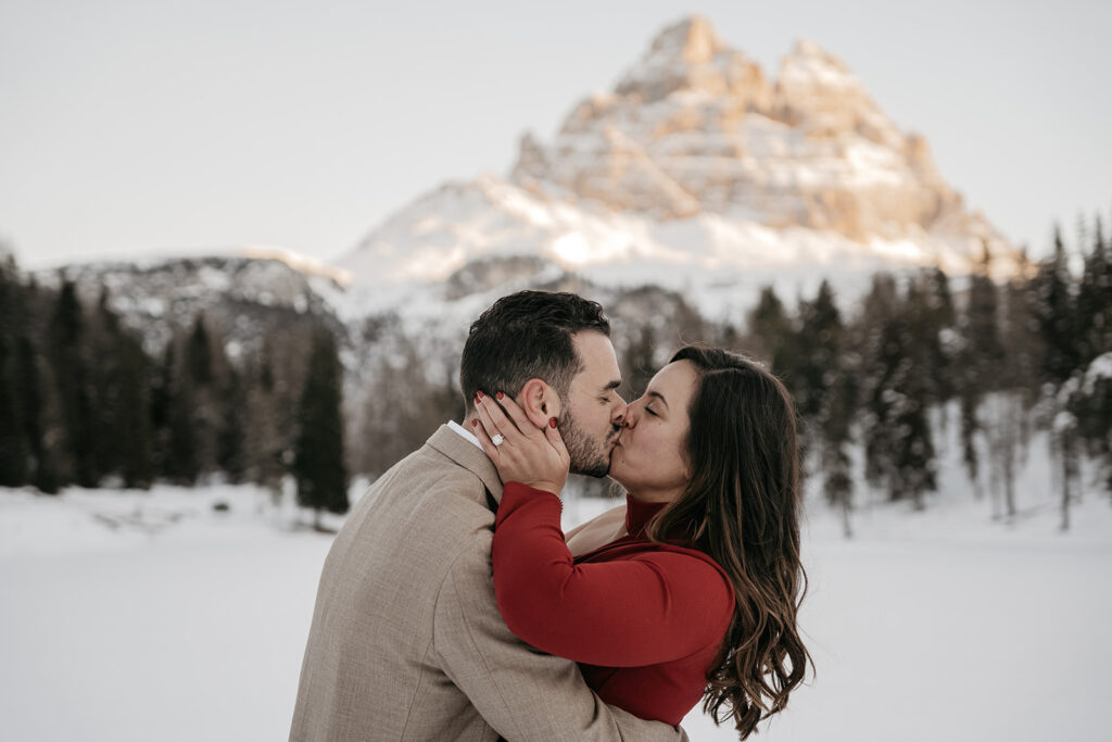 Couple kissing in snowy mountain landscape.