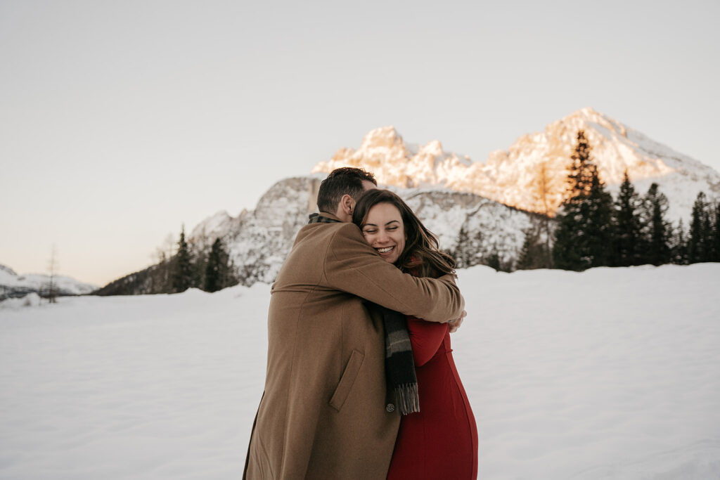 Couple hugging in snowy mountain landscape.