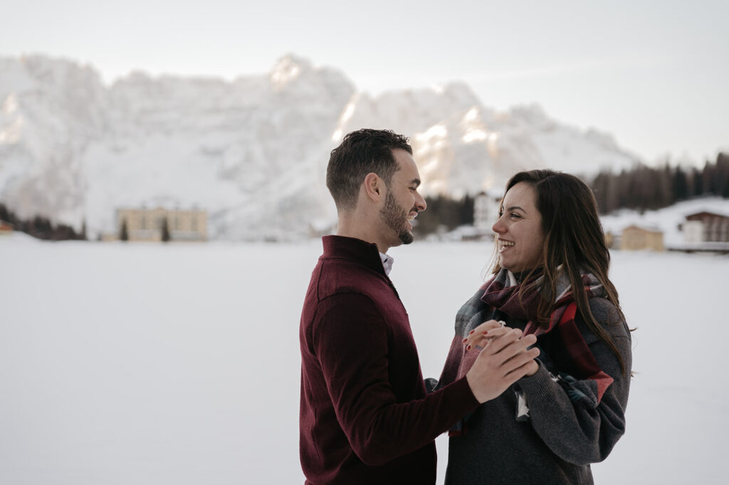 Couple smiling in snowy mountain setting.