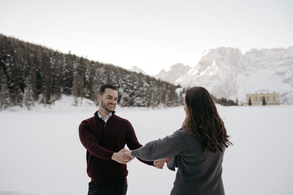 Couple holds hands in snowy landscape.