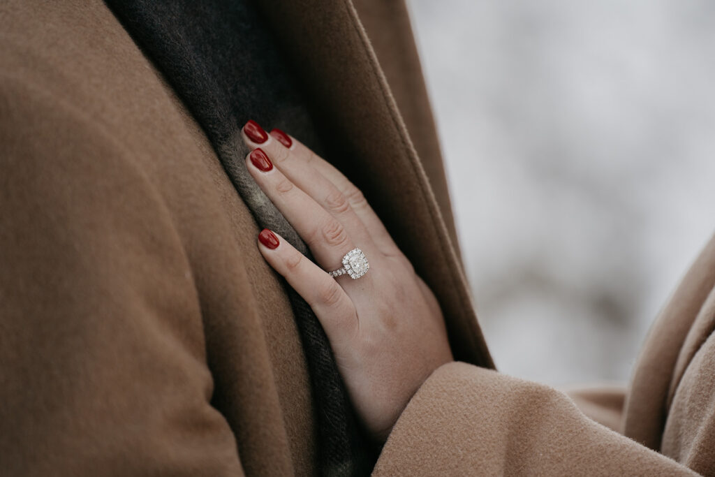 Woman's hand with engagement ring on coat