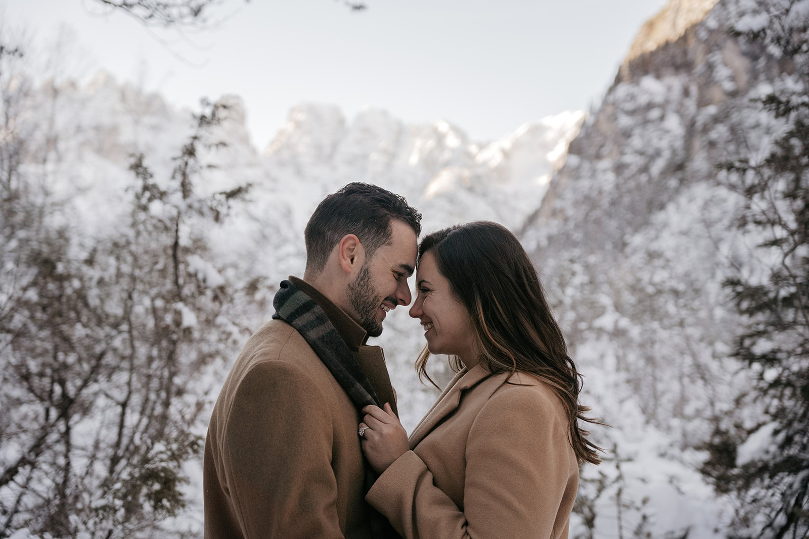 Couple smiling in snowy mountain landscape.