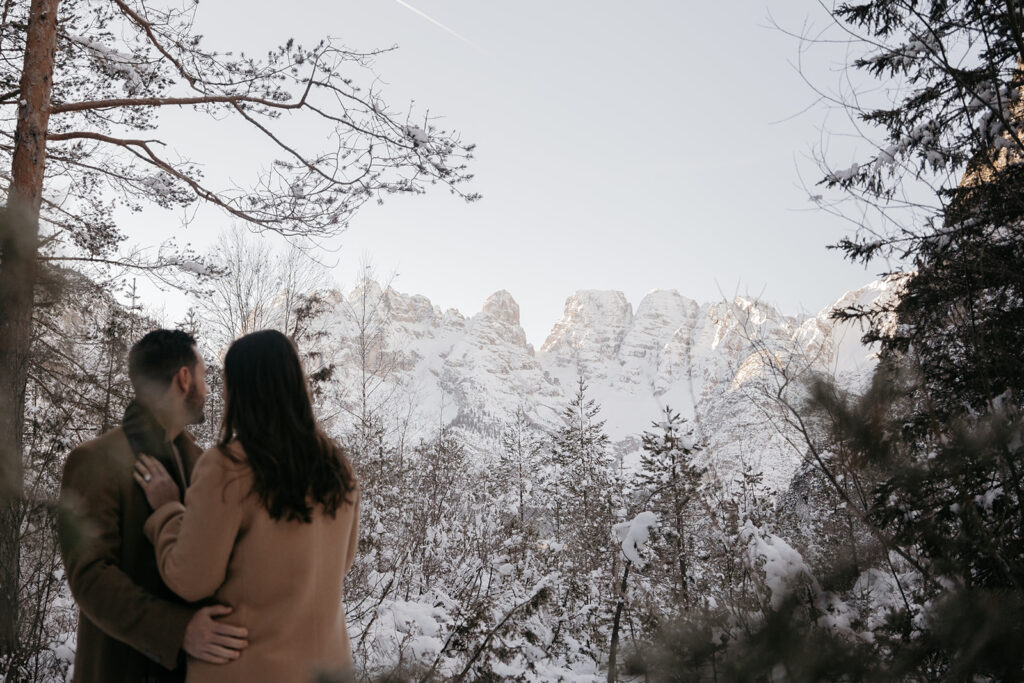 Couple gazes at snow-covered mountain landscape.