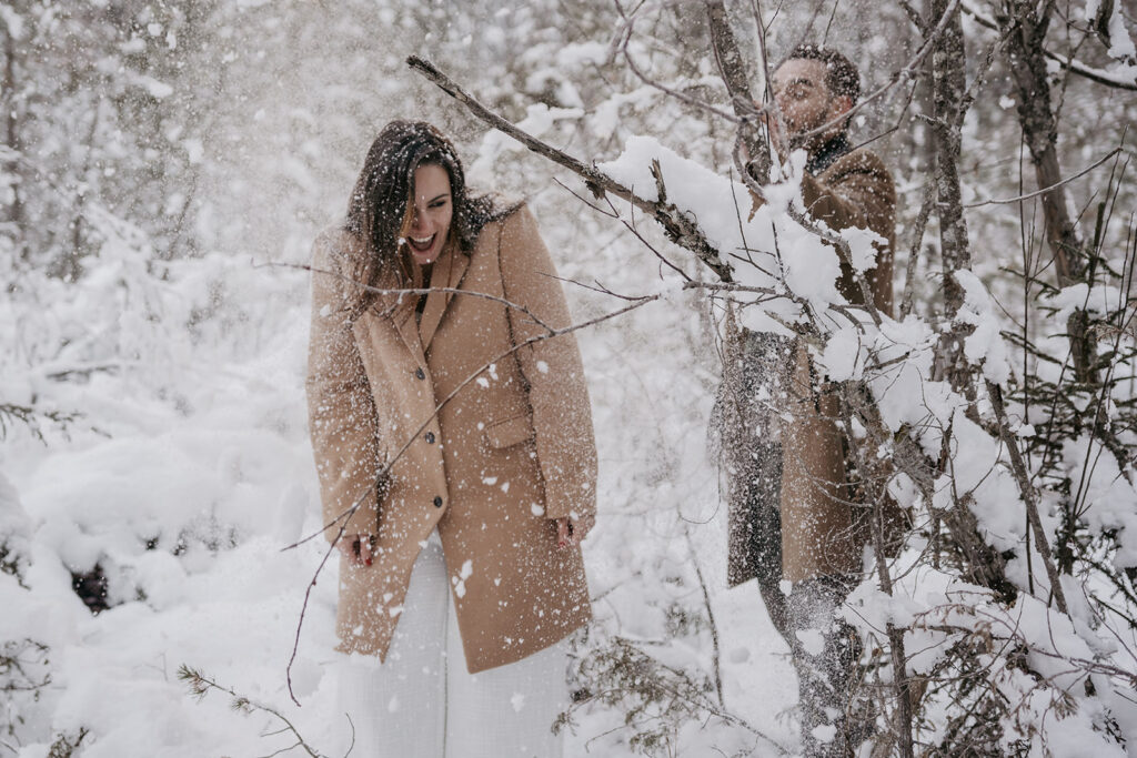 Couple enjoying snow in winter forest scene.