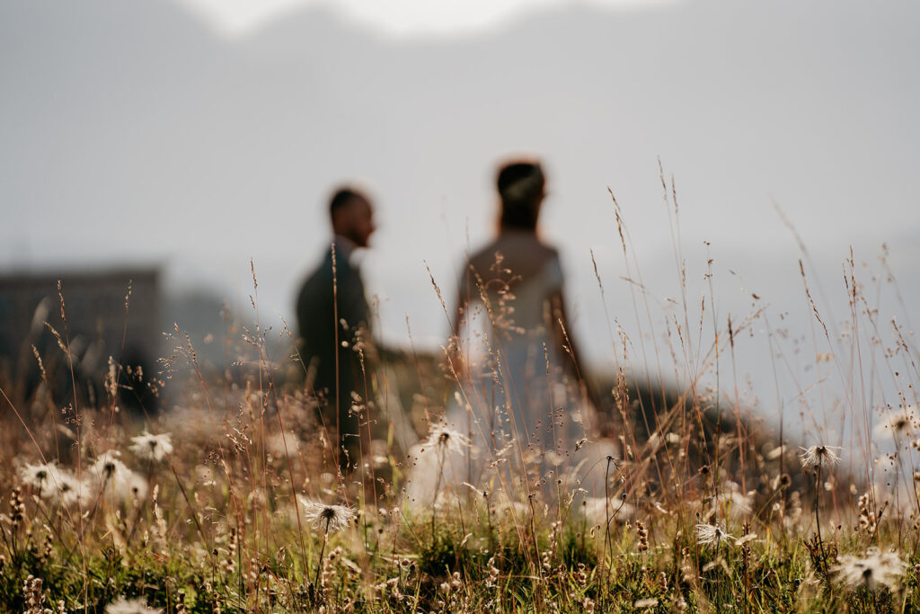 Blurred couple in grassy field with mountains