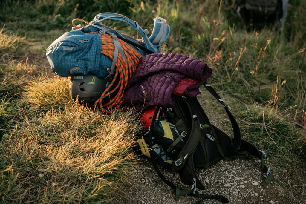 Hiking gear with backpack and climbing ropes outdoors.