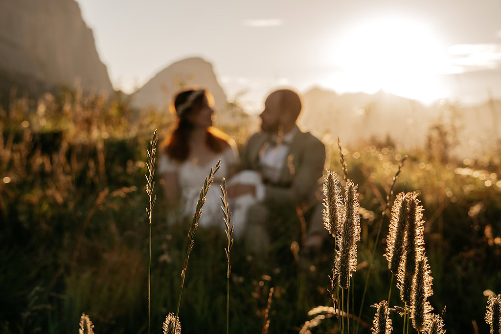 Couple sitting in sunlit meadow at sunset.