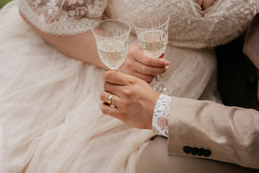 Couple holding champagne glasses, wedding attire visible.