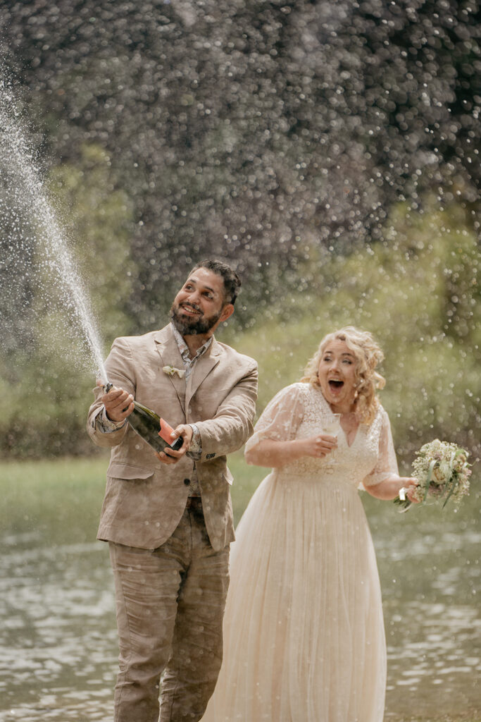 Bride and groom celebrating with champagne outdoors.