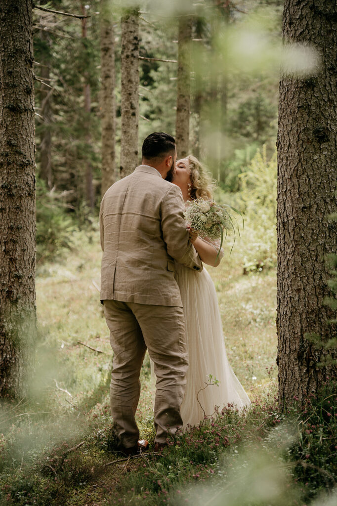 Couple kissing in a forest wedding ceremony.