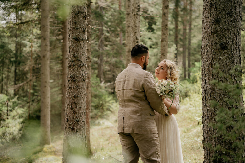 Couple embracing in a serene forest setting.