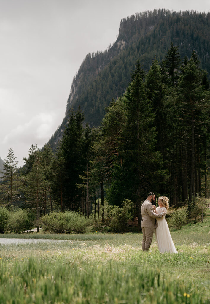 Couple embraces in scenic forest clearing.