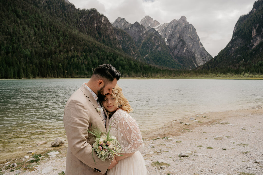 Couple embracing by lake with mountain backdrop