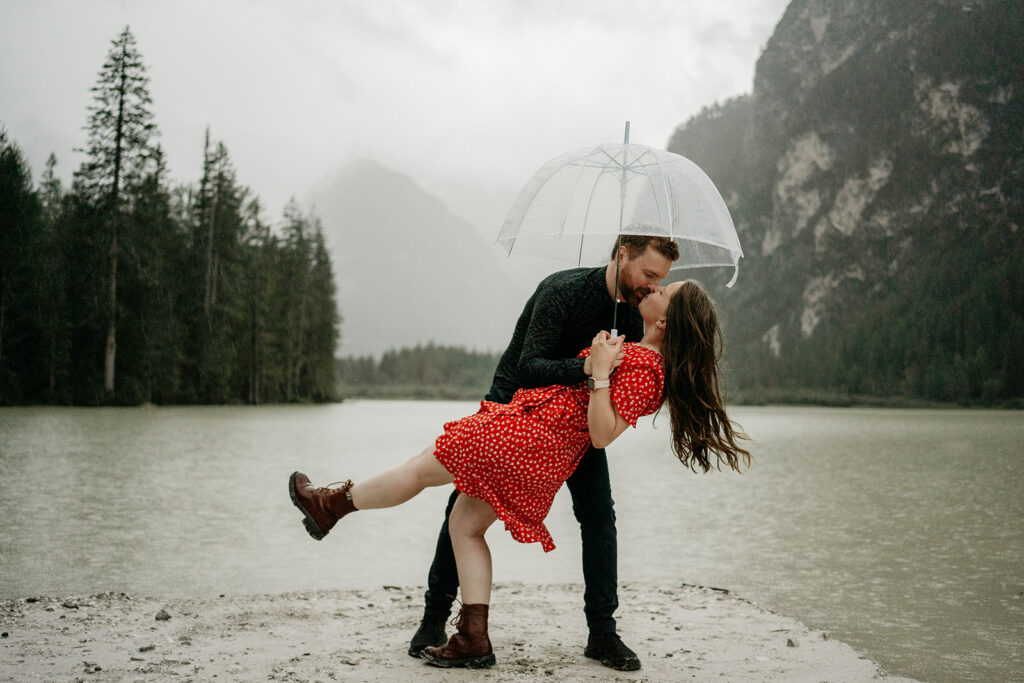 Couple dancing by lake under umbrella