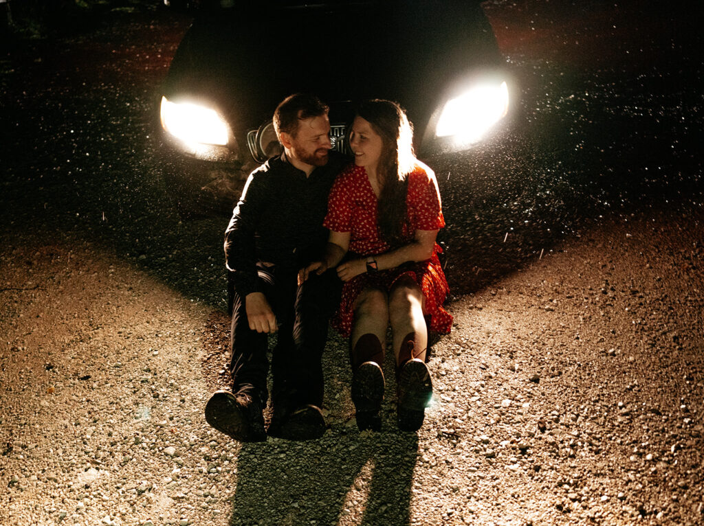 Couple sitting by a car at night