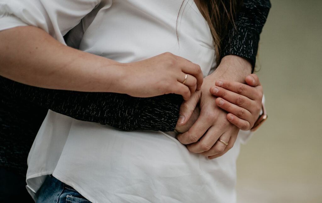 Couple holding hands with wedding rings.