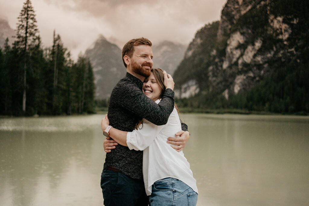 Couple hugging by a scenic lake.