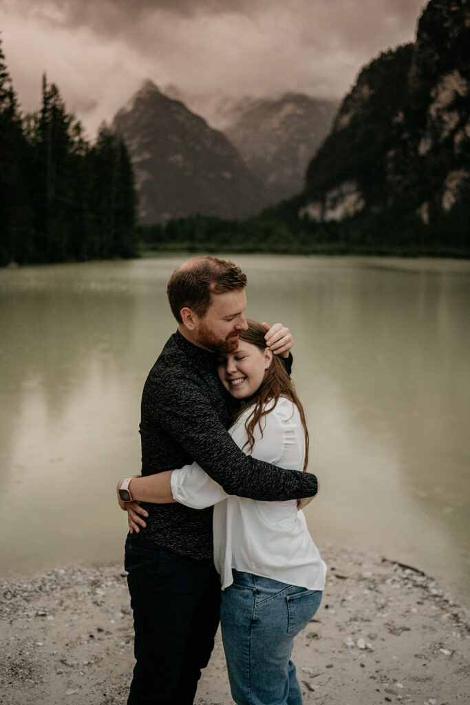 Couple embracing by a mountain lake at sunset.