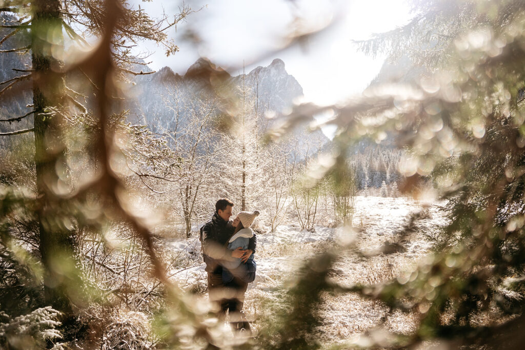 Couple embracing in a snowy forest landscape.