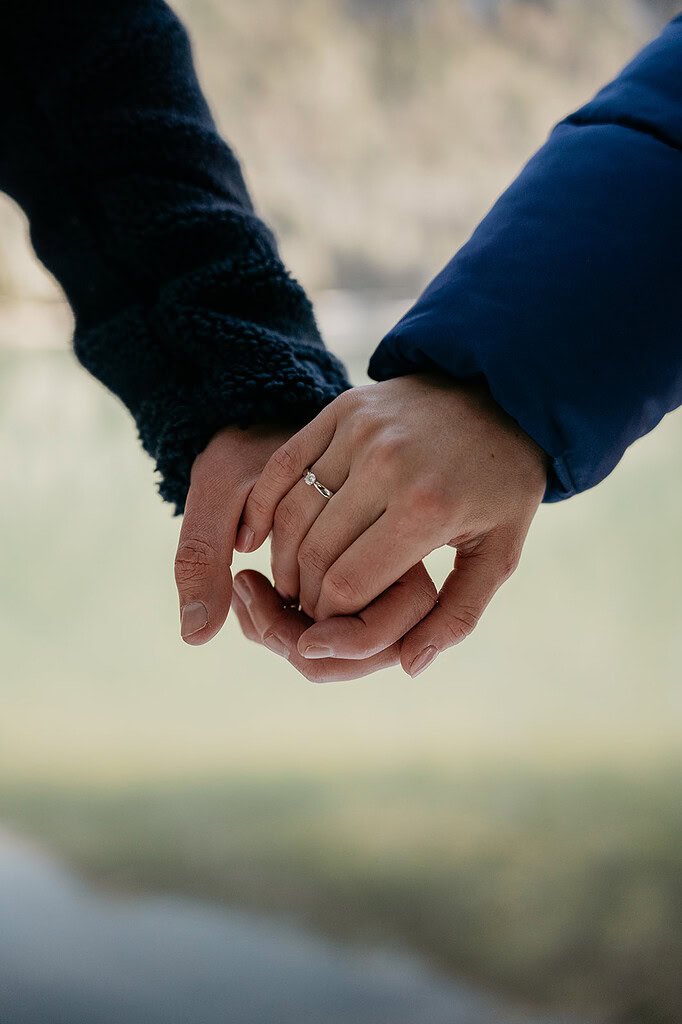 Closeup of hands holding with engagement ring.